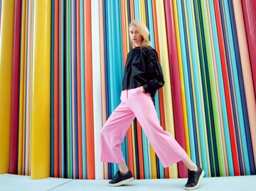 Portrait einer jungen Frau vor einem bunt gestreiften Hintergrund | © Getty Images/Andriy Onufriyenko