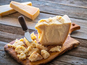 Parmesan Käse am Stück auf einem Brett mit Messer | © Getty Images/MEDITERRANEAN