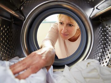Frau legt Wäsche in den Trockner | © Adobe stock/Monkey Business