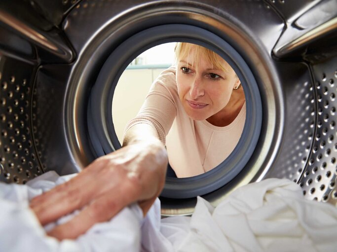 Frau legt Wäsche in den Trockner | © Adobe stock/Monkey Business