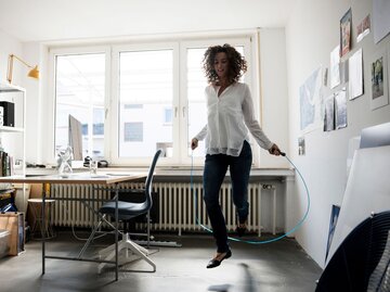 Eine Frau beim Seilspringen vor ihrem Schreibtisch | © Getty Images / 	Westend61