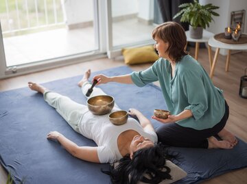 Eine Frau bekommt eine Klangschalen-Massage | © Getty Images / Dobrila Vignjevic