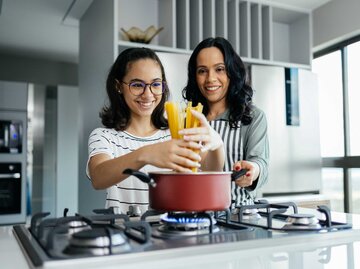 Mutter und Tochter kochen gemeinsam Nudeln | © Adobe Stock/kleberpicui