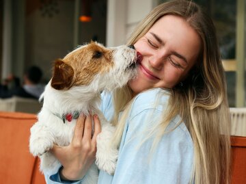 Junge Frau kuschelt mit einem kleinen Hund | © Adobe Stock/Evrymmnt