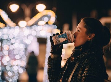 Frau trinkt Glühwein auf einem Weihnachtsmarkt | © Unsplash/freestocks