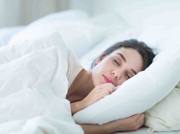 Frau schläft auf der Seite in einem Bett | © Getty Images/Tetra Images