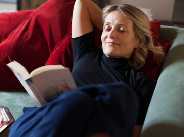 Frau liegt auf der Couch und liest ein Buch | © Getty Images/Kathrin Ziegler