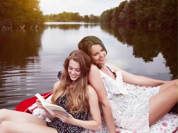Mutter und Tochter sitzen in einem Boot auf dem Wasser und lesen ein Buch | © Getty Images/Silke Woweries