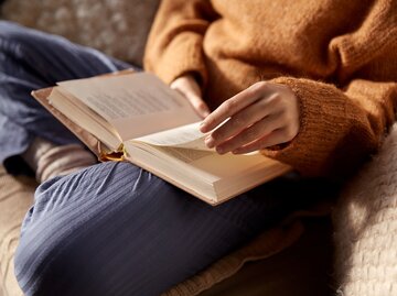 Eine Frau hat ein Buch auf dem Schoß und liest es | © Adobe Stock/Syda Productions