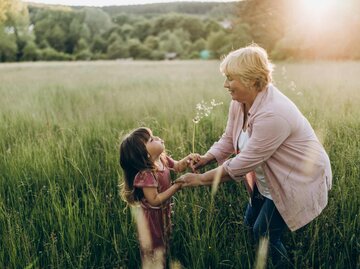 Großmutter und Enkelkind tollen auf einer Wiese herum | © Getty Images/Liliya Krueger