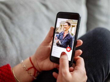 Frau hält Handy mit geöffneter Dating-App in der Hand | © Getty Images/Luis Alvarez