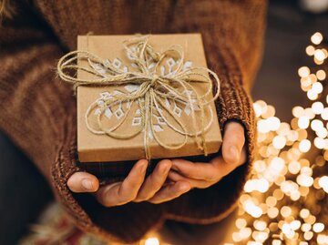 Person mit Weihnachtsgeschenk in den Händen | © Getty Images/Liliya Krueger