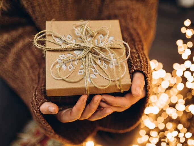 Person mit Weihnachtsgeschenk in den Händen | © Getty Images/Liliya Krueger