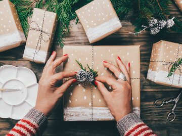 Eine Frau packt Weihnachtsgeschenke ein. | © Adobe Stock/asife