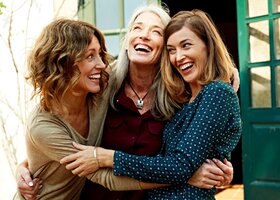 Drei Freundinnen über 40 lachen gemeinsam