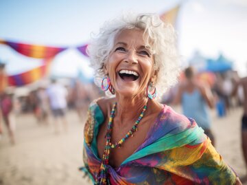  Porträt einer glücklichen älteren Frau, die bei einer Strandparty am Strand tanzt | © Adobe Stock/Inigo