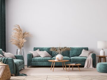 Wohnzimmer mit weißen Wänden, grünem Sofa und hellbraunen Holztischen | © AdobeStock/lilasgh
