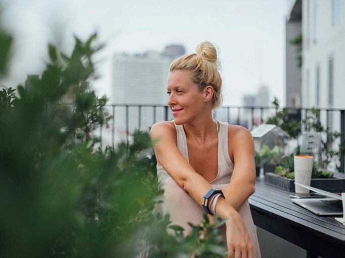 Frau sitzt lächelnd auf ihrem Balkon | © Getty Images/Lumina Images