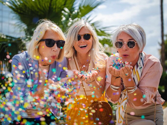 Drei reife Frauen haben Spaß und werfen Konfetti | © Getty Images/wundervisuals
