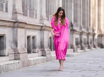 Streetstyle von Frau in pinkem Kleid mit pinker Tasche | © Getty Images/Edward Berthelot