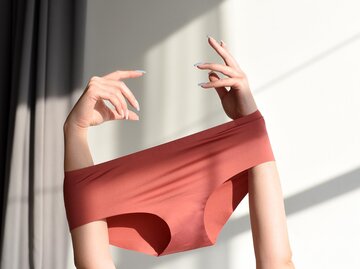 Frauenarme mit übergestülpter, nahtloser Unterhose in Rot | © Getty Images/Maryna Terletska