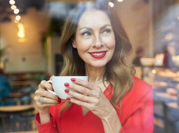 Frau mit Kaffeetasse und rotem Oberteil | © Getty Images/Westend61