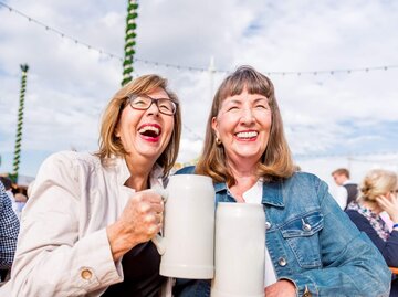 Zwei Personen stoßen mit Bierkrügen an | © Getty Images/EMS-FORSTER-PRODUCTIONS