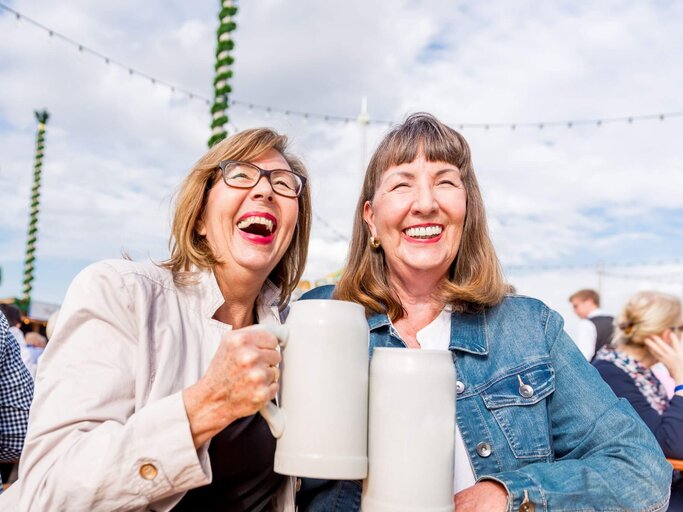 Zwei Personen stoßen mit Bierkrügen an | © Getty Images/EMS-FORSTER-PRODUCTIONS