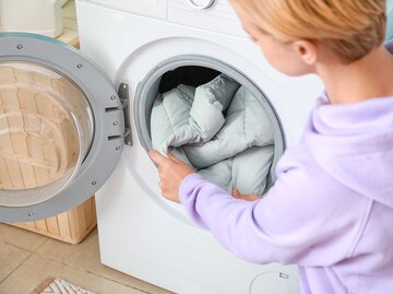 Frau legt eine Daunenjacke in die Waschmaschine. | © Adobe Stock/Pixel-Shot