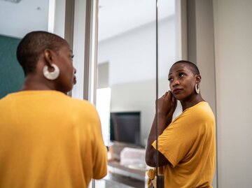 Person zieht Ohrringe vor Spiegel an | © Getty Images/FG Trade