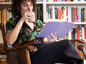 Person liest Buch in Sessel | © Getty Images/Luis Alvarez