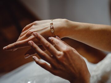 Detailaufnahme von Frauenhänden, die ein Armband anlegen | © AdobeStock/Oleksandr
