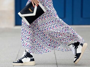 Nahaufnahme einer Frau, die einen Maxirock und Sneakers trägt | © Getty Images/Streetstyleshooters 