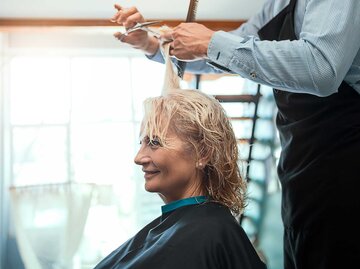 Ältere Frau sitzt beim Friseur und bekommt die Haare geschnitten.  | © Getty Images / Nastasic