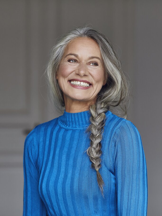 Schöne Frau mit grauen Haaren, die zu einer Flechtfrisur gestylt sind | © GettyImages/Westend61