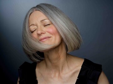 Attraktive, reife Frau mit grauen Haaren schüttelt ihr Haar | © Getty Images/Ralf Nau