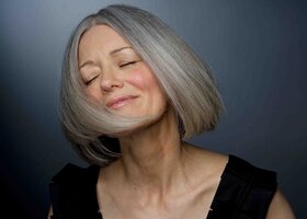 Attraktive, reife Frau mit grauen Haaren schüttelt ihr Haar