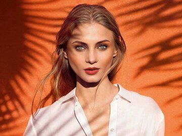 Portrait einer geschminkten Frau mit roten Lippen und Bronzer | © Clarins, David Burton