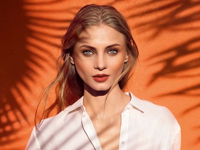 Portrait einer geschminkten Frau mit roten Lippen und Bronzer | © Clarins, David Burton