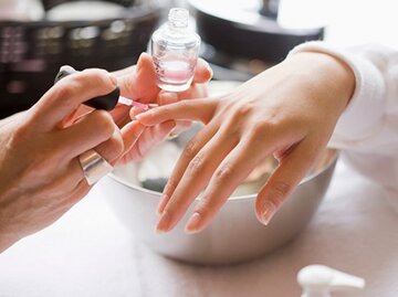 Hand der gerade von einer anderen Person ein Nagel lackiert wird mit Klar | © Jim Craigmyle, Getty Images