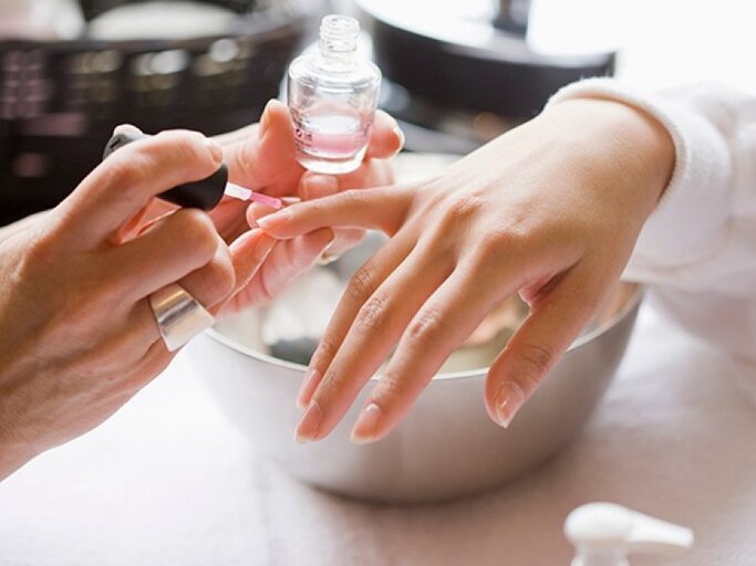 Hand der gerade von einer anderen Person ein Nagel lackiert wird mit Klar | © Jim Craigmyle, Getty Images