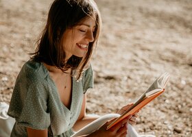 Frau in sommerlichem Kleid liest ein Buch
