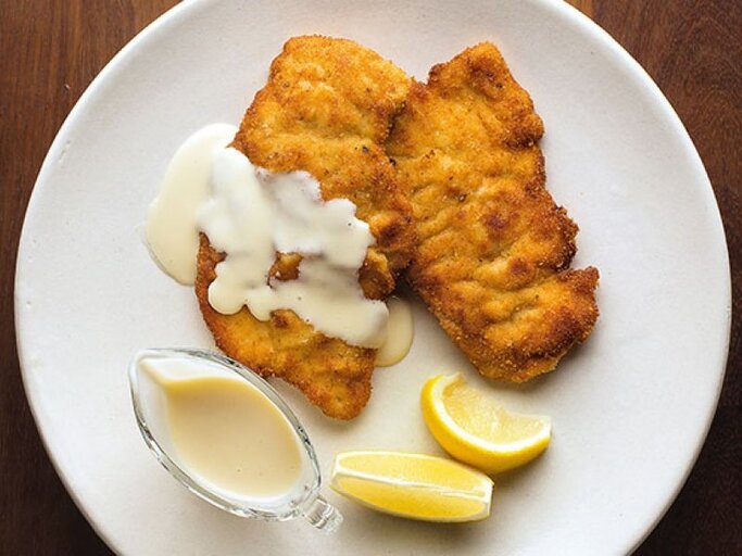 Nahaufnahme eines Schnitzels mit Béchamelsauce. | © Craig Fraser