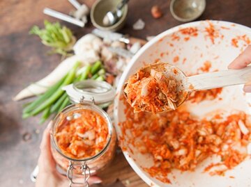 Kimchi wird von einer Schüssel in ein Glas gelöffelt. | © Lucia Lambriex, Getty Images