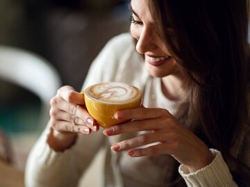 Frau lächelt, während sie ihren Kaffee genießt | © gettyimages.de /  Drazen Zigic