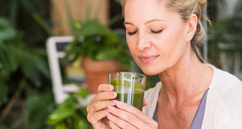 Reife Frau trinkt einen Smoothie mit Gerstengras und ist entspannt | © Getty Images / Westend61