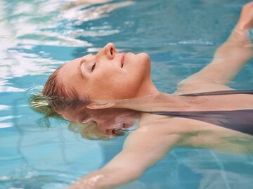 Frau liegt entspannt im Wasser zur Vorbeugung eines Bandscheibenvorfalls. | © PeopleImages, Getty Images