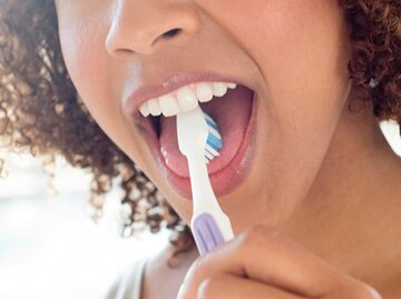 Dunkelhäutige Frau die sich mit der Zahnbürste die Zunge putzt | © Science Photo Library, Getty Images
