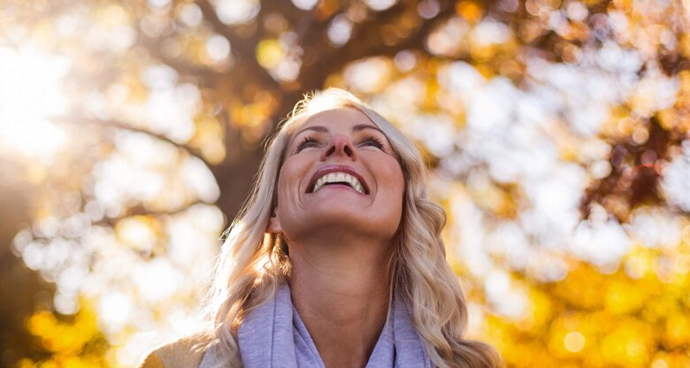 Frau blickt glücklich in die Herbstsonne | © gettyimages.de / Wavebreakmedia