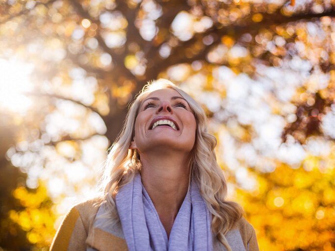 Frau blickt glücklich in die Herbstsonne | © gettyimages.de / Wavebreakmedia